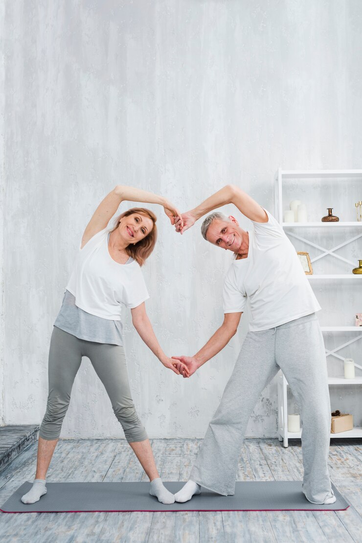 joyful-senior-couple-making-heart-shape-with-their-hands-while-exercising-home_23-2148097413